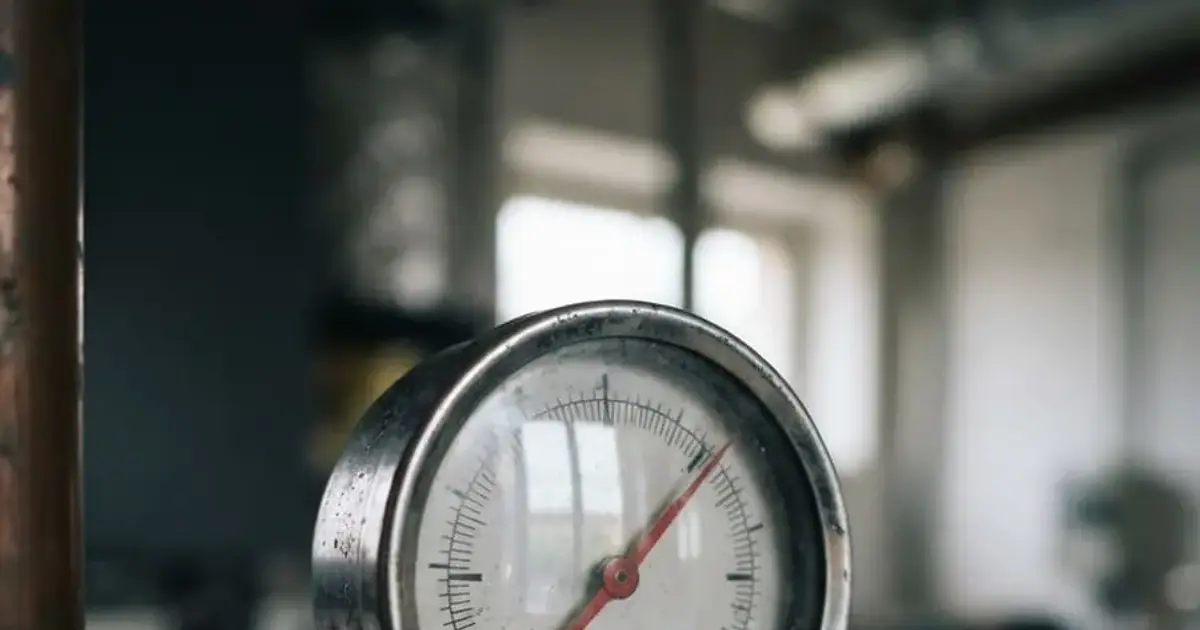 Manometre de chaudiere a cadran blanc et aiguille rouge, fixe sur un tube cuivre